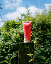 Tube de gel douche posé sur une bûche de bois en pleine nature.