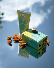 Un tube de crème mains et un shampoing solide de la marque ONA COSMEHTIK entourés d'amandes. 