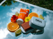 Composition de produits cosmétiques entourés d'agrumes et de fleurs oranges et jaunes.